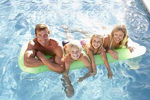 Family Outside Relaxing In Swimming Pool