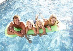 Family Outside Relaxing In Swimming Pool