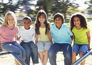 Group Of Children Riding On Roundabout In Playground