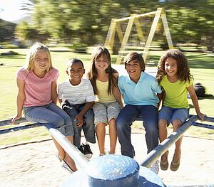 Group Of Children Riding On Roundabout In Playground