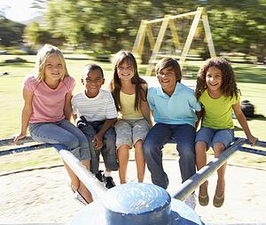 Group Of Children Riding On Roundabout In Playground