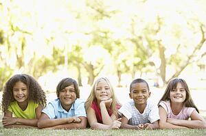 Group Of Children Lying On Stomachs In Park