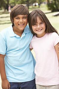 Two Children In Park Giving Each Other Hug