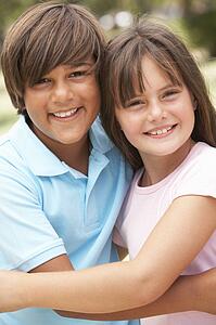 Two Children In Park Giving Each Other Hug