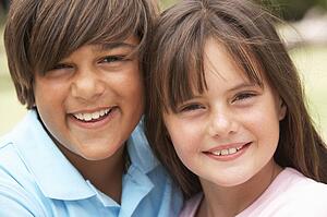 Two Children In Park Giving Each Other Hug
