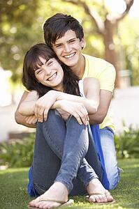 Portrait Of Romantic Teenage Couple Sitting In Park