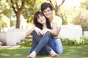 Portrait Of Romantic Teenage Couple Sitting In Park
