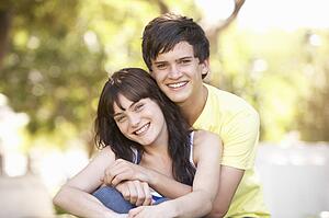 Portrait Of Romantic Teenage Couple Sitting In Park