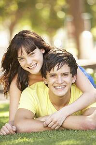 Portrait Of Romantic Teenage Couple Sitting In Park