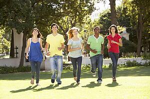 Group Of Teenagers Running Through Park