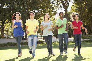 Group Of Teenagers Running Through Park