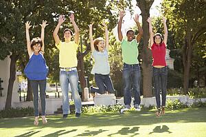 Group Of Teenagers Jumping In Air In Park