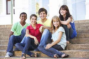 Group Of Teenage Friends Sitting On College Steps Outside