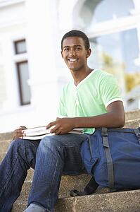 Male Teenage Student Sitting Outside On College Steps