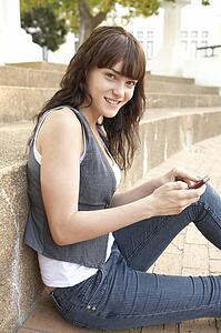 Teenage Student Sitting Outside On College Steps Using Mobile Phone
