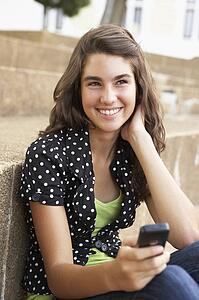 Teenage Student Sitting Outside On College Steps Using Mobile Phone