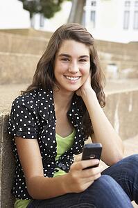 Teenage Student Sitting Outside On College Steps Using Mobile Phone