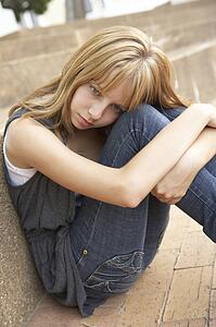 Unhappy Female Teenage Student Sitting Outside On College Steps Using Mobile Phone