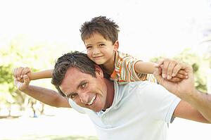 Father Giving Son Ride On Back In Park