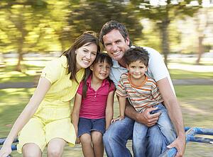Family Riding On Roundabout In Park