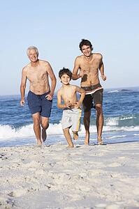 Grandfather, Father and Grandson Running Along Beach