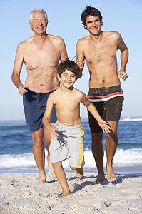 Grandfather, Father and Grandson Running Along Beach