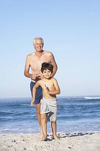 Grandfather, Father and Grandson Running Along Beach
