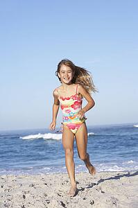 Young Girl Running Along Sandy Beach