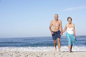 Senior Couple On Holiday Running Along Sandy Beach