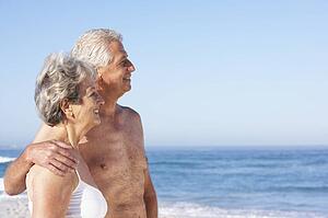 Senior Couple On Holiday Walking Along Sandy Beach