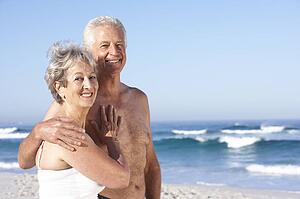 Senior Couple On Holiday Walking Along Sandy Beach