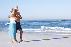 Senior Couple On Holiday Walking Along Sandy Beach