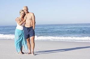 Senior Couple On Holiday Walking Along Sandy Beach