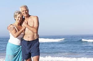 Senior Couple On Holiday Walking Along Sandy Beach