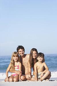 Young Family Relaxing On Beach Holiday