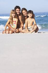Young Family Relaxing On Beach Holiday