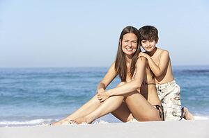 Mother And Son Relaxing Together On Beach Holiday