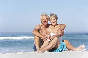 Senior Couple On Holiday Sitting On Sandy Beach
