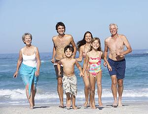 Three Generation Family On Holiday Walking Along Beach