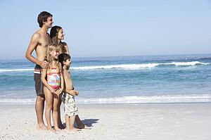 Young Family Standing On Sandy Beach on Holiday