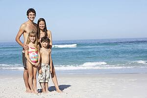Young Family Standing On Sandy Beach on Holiday