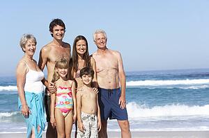Three Generation Family On Holiday Walking Along Beach