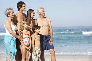 Three Generation Family On Holiday Walking Along Beach