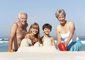 Grandparents And Grandchildren Building Sandcastles Together On Beach Holiday
