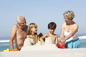 Grandparents And Grandchildren Building Sandcastles Together On Beach Holiday