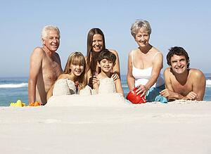 Three Generation Family Building Sandcastles On Beach Holiday