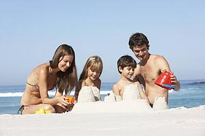 Family Building Sandcastles On Beach Holiday