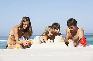 Family Building Sandcastles On Beach Holiday