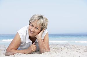 Senior Woman Relaxing On Sandy Beach