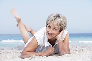 Senior Woman Relaxing On Sandy Beach